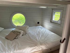 Cama blanca en habitación pequeña con ventana en La Tiny du paradis en Baigts-de-Béarn