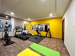 a gym with exercise equipment and a yellow wall at Hotel One Sahiwal in Sāhīwāl