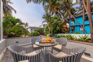a table and chairs on a balcony with palm trees at StayVista at Mawi Infinitty Beach View Villa - Arambol in Arambol