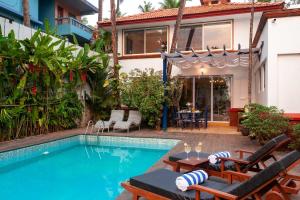 a house with a swimming pool with chairs and a table at StayVista at Mawi Infinitty Beach View Villa - Arambol in Arambol