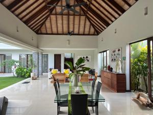 uma sala de estar aberta com uma mesa de vidro e cadeiras em Oshan Villas Bali em Canggu