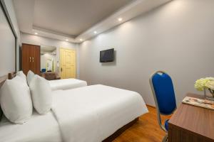 a bedroom with two white beds and a blue chair at La Renta Center Hotel & Spa in Hanoi