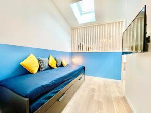 - un canapé bleu dans une chambre avec une lucarne dans l'établissement Niort - Hyper-Centre - Appartements en Duplex ou Triplex - Wifi Fibre - NOUVEAU, à Niort