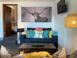 a living room with a blue couch with a bull painting on the wall at Dolphin Circle Bed and Breakfast in Plettenberg Bay