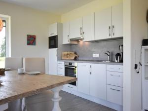 a kitchen with white cabinets and a wooden table at Mein-Ostseeplätzchen Haus am Meer 7 in Niesgrau