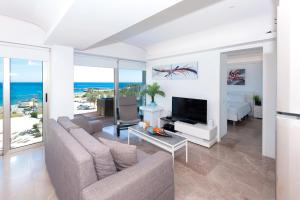Sala de estar con sofá y TV y el océano en Apartment Marina - Beachfront, en Protaras