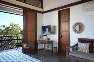 Schlafzimmer mit einem Bett, einem Tisch und einem TV in der Unterkunft Atelier TE Designer Guesthouse in Sanur