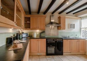 a kitchen with wooden cabinets and a stove top oven at Kingston House in West Witton