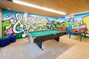 einen Billardtisch in einem Zimmer mit einer Graffiti-Wand in der Unterkunft Reka-Feriendorf Urnäsch in Urnäsch