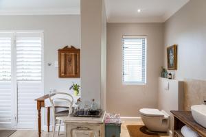 a bathroom with a sink and a toilet and a table at Nerf-af ROOMS at Onrus , Hermanus in Hermanus
