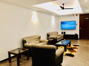 a living room with couches and a flat screen tv at Tropic Inn - Mount Lavinia in Watumulla