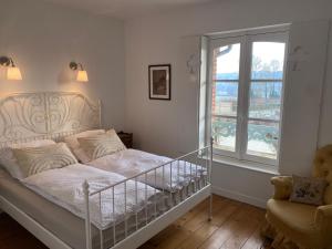 a white bedroom with a bed and a window at La Maison du Cavalier, Chateau de lAvenue in Pierrefitte-en-Auge