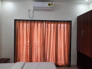 a bedroom with an orange curtain and a television at Raapan Beach Resort in Malvan