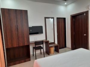 a bedroom with a desk and a tv and a chair at Raapan Beach Resort in Malvan