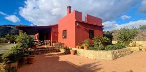 a red house with a brick walkway in front of it at TODIMER FINCA ALPUJAREÑA in Vélez de Benaudalla