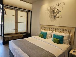 a bedroom with a large bed with green and white pillows at Blue Breeze - Jetwing Select in Negombo