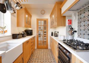 uma cozinha com armários de madeira e um forno com placa de fogão em Honey Cottage em Richmond