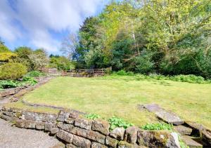 a stone wall in a yard with a grass field at Hollins Cottage in Grosmont