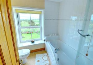 a bathroom with a tub and a toilet and a window at Hole In The Ellers in Lealholm +8 photos