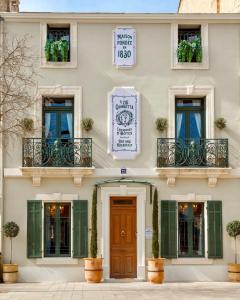 um edifício com persianas verdes e uma porta de madeira em Le 215 Gambetta boutique hôtel en Provence em Cavaillon