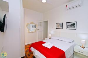 een witte slaapkamer met een bed met een rode deken bij Adorável 2 quartos em predio ART-DECOR in Rio de Janeiro