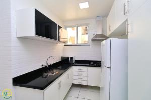 een witte keuken met een wastafel en een koelkast bij Adorável 2 quartos em predio ART-DECOR in Rio de Janeiro
