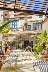 un patio avec des tables et des chaises et un bâtiment dans l'établissement Le 215 Gambetta boutique hôtel en Provence, à Cavaillon