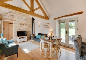 a living room with a table and chairs and a stone wall at Hog Barn at Howe End in Castleton