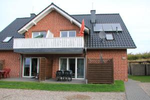 a red brick house with a balcony and a solarium at Familienwohnung MANDO in Neue Tiefe Fehmarn