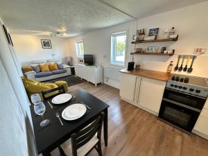 uma cozinha e uma sala de estar com uma mesa num quarto em Peninsula Cottage em Garrabost