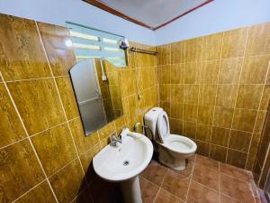 y baño con aseo, lavabo y espejo. en Mangala Lodge, en Kurunegala