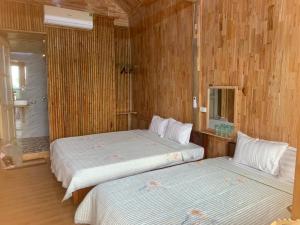 two beds in a room with wooden walls at Green Homestay Mai Chau in Mai Châu