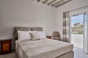 a white bedroom with a bed and a window at Philippi Villa in Mýkonos City
