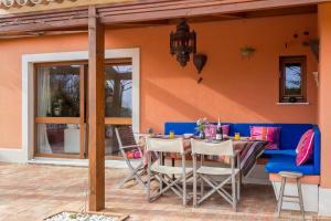un patio con mesa y sillas y un sofá azul en Quinta Tannamara villa private pool & garden, en Burgau