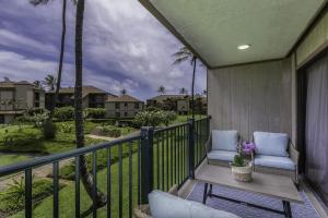 a balcony with two chairs and a table and palm trees at Pono Kai H204 condo in Kapaa