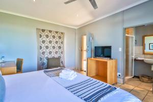 um quarto de hotel com uma cama e uma televisão em Villa Paradiso em Hartbeespoort