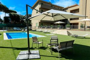 a yard with chairs and an umbrella and a pool at Residence San Francesco in Tirrenia