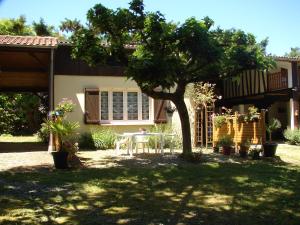 un patio con una mesa y un árbol delante de una casa en Gites Le Grand Jardin, en Puydarrieux