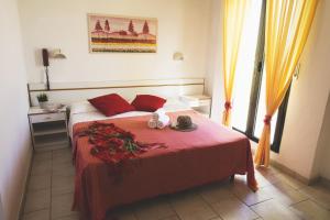 a bedroom with a bed with red sheets and flowers on it at Hotel Reyt in Rimini