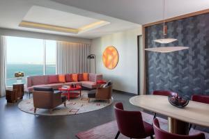 a living room with a couch and a table and chairs at Andaz Doha, A Concept by Hyatt in Doha