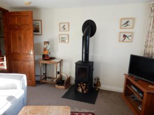 un soggiorno con stufa a legna in un angolo di Kilsby Cottage a Llanwrtyd Wells Altre 7 foto