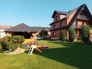 uma casa com um parque infantil no quintal em Iwonka Tylicz Pokoje i Apartamenty em Tylicz