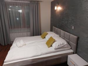 uma cama grande com lençóis brancos e almofadas amarelas em Iwonka Tylicz Pokoje i Apartamenty em Tylicz