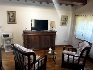a living room with two chairs and a flat screen tv at Charming Townhouse with Garden in Impruneta