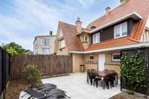 een achtertuin met een tafel en stoelen en een hek bij Maison Emile in De Panne