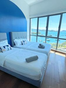 Dos camas en una habitación con una gran ventana. en Mari Mari Homestay - IMAGO THE LOFT, en Kota Kinabalu