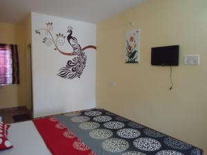 a room with a bed with a peacock painting on the wall at Silver Moon Guest House in Mahabalipuram