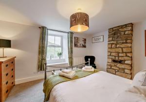 a bedroom with a bed and a stone wall at High Green Cottage in Low Eskcleth
