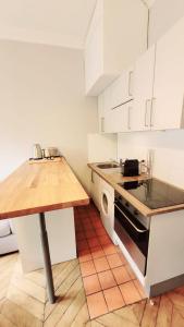 eine Küche mit weißen Schränken und einer Holzarbeitsplatte in der Unterkunft Le Cyrano - Versailles in Versailles