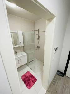 a white bathroom with a shower and a sink at Reina Apartment - near abi qarshia and old town in Prizren